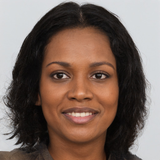 Joyful black young-adult female with long  brown hair and brown eyes
