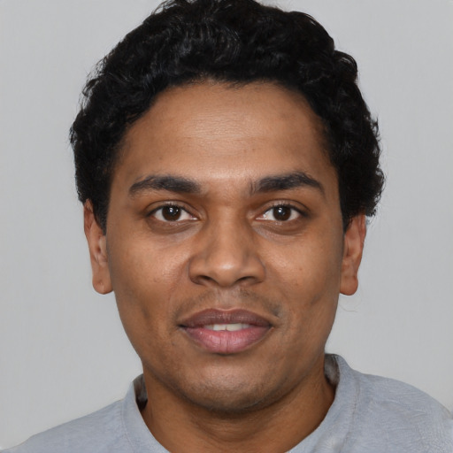 Joyful black young-adult male with short  black hair and brown eyes