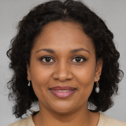 Joyful black adult female with long  brown hair and brown eyes