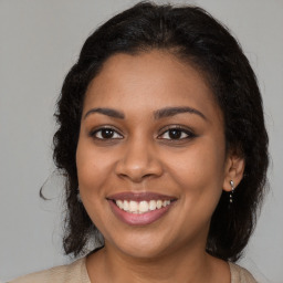 Joyful black young-adult female with long  brown hair and brown eyes