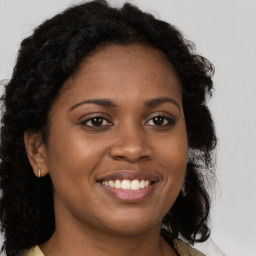 Joyful black young-adult female with long  brown hair and brown eyes