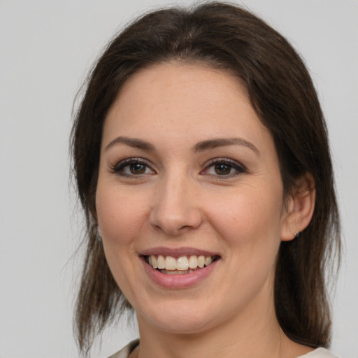 Joyful white young-adult female with medium  brown hair and grey eyes