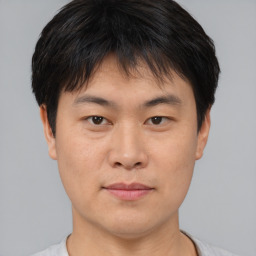 Joyful asian young-adult male with short  brown hair and brown eyes