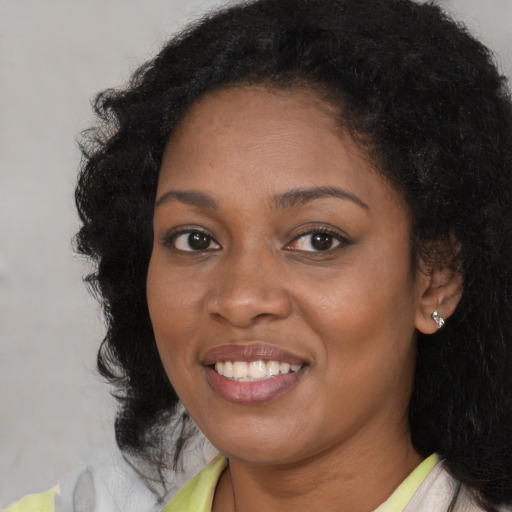 Joyful black young-adult female with long  black hair and brown eyes