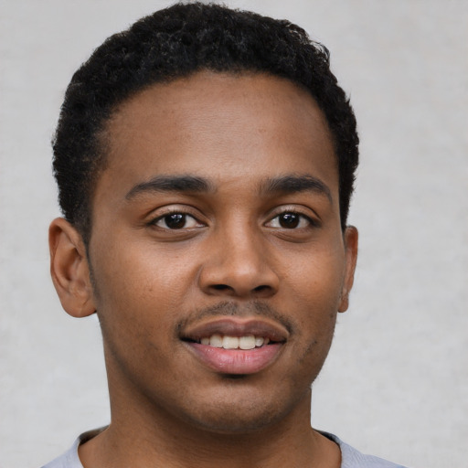 Joyful black young-adult male with short  black hair and brown eyes