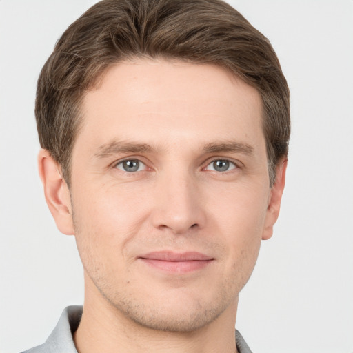 Joyful white young-adult male with short  brown hair and grey eyes