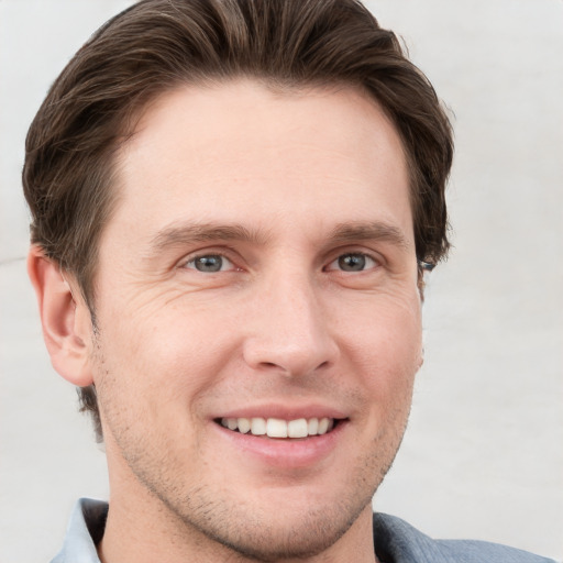 Joyful white young-adult male with short  brown hair and grey eyes