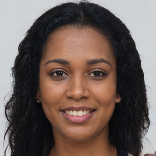 Joyful black young-adult female with long  black hair and brown eyes