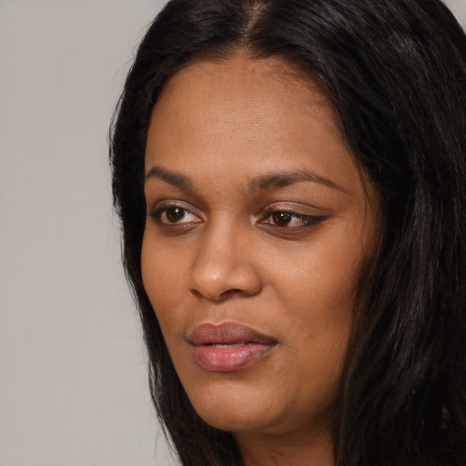 Joyful black young-adult female with long  black hair and brown eyes