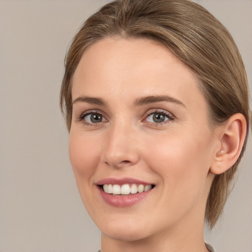 Joyful white young-adult female with medium  brown hair and grey eyes