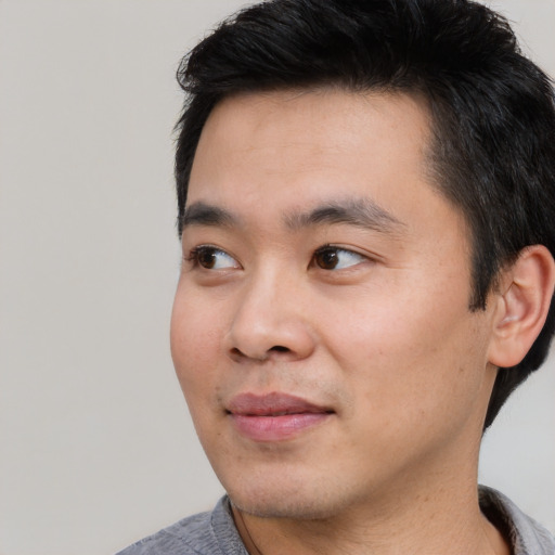 Joyful asian young-adult male with short  black hair and brown eyes