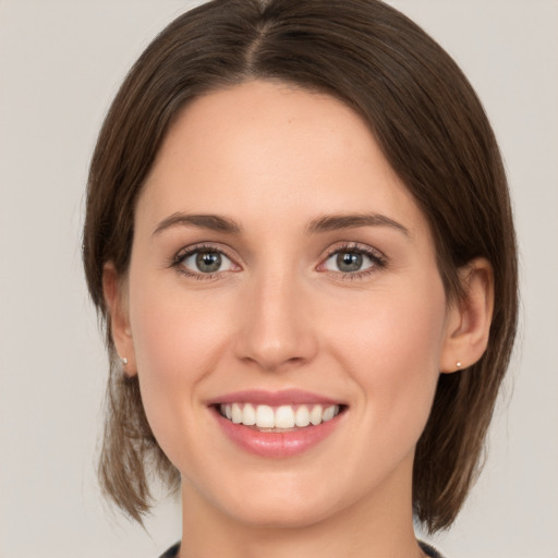 Joyful white young-adult female with medium  brown hair and green eyes