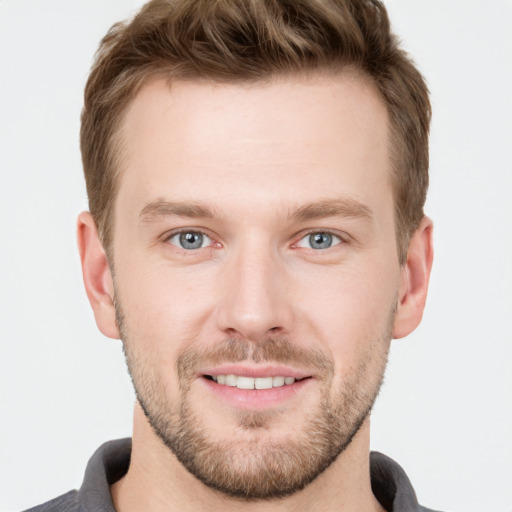 Joyful white young-adult male with short  brown hair and grey eyes