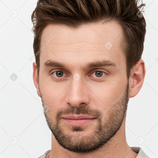 Joyful white young-adult male with short  brown hair and grey eyes