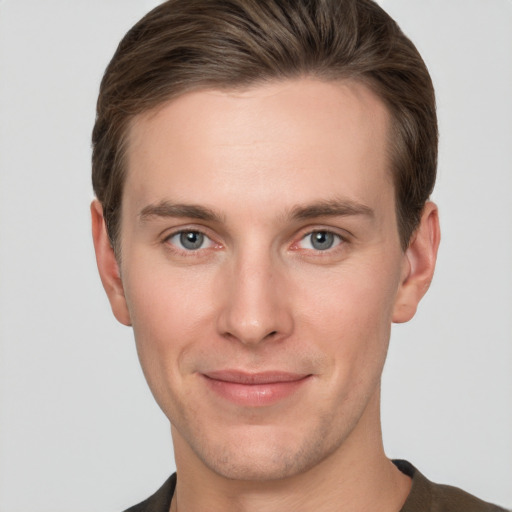 Joyful white young-adult male with short  brown hair and grey eyes