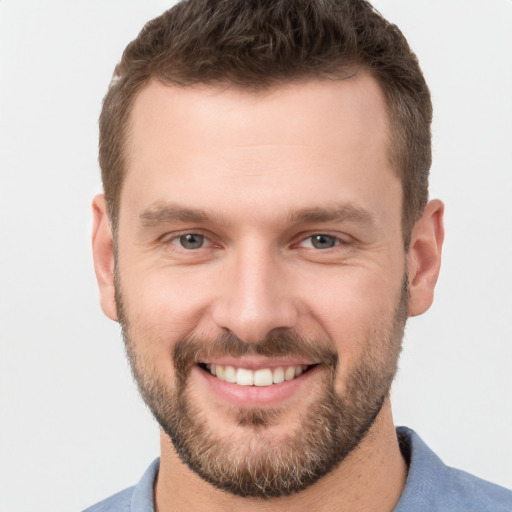 Joyful white young-adult male with short  brown hair and grey eyes