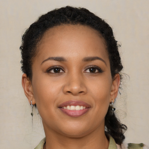 Joyful black young-adult female with long  brown hair and brown eyes