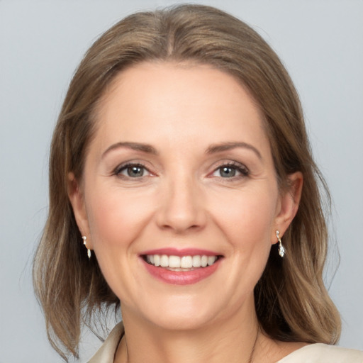 Joyful white young-adult female with medium  brown hair and grey eyes