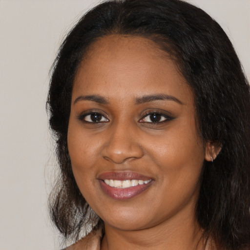 Joyful black young-adult female with long  black hair and brown eyes