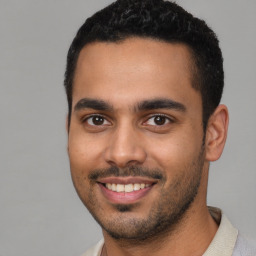 Joyful latino young-adult male with short  black hair and brown eyes