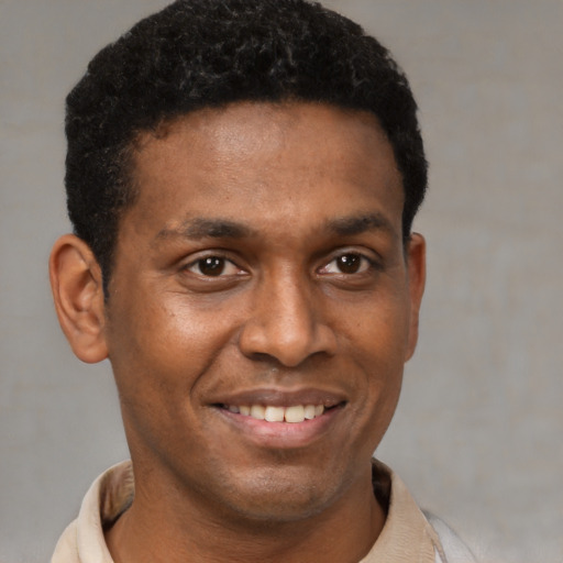 Joyful black young-adult male with short  black hair and brown eyes