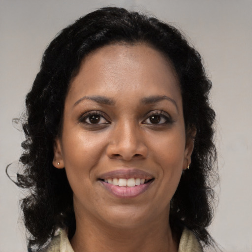 Joyful black young-adult female with long  brown hair and brown eyes