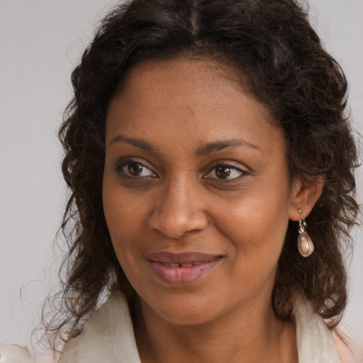Joyful black young-adult female with long  brown hair and brown eyes