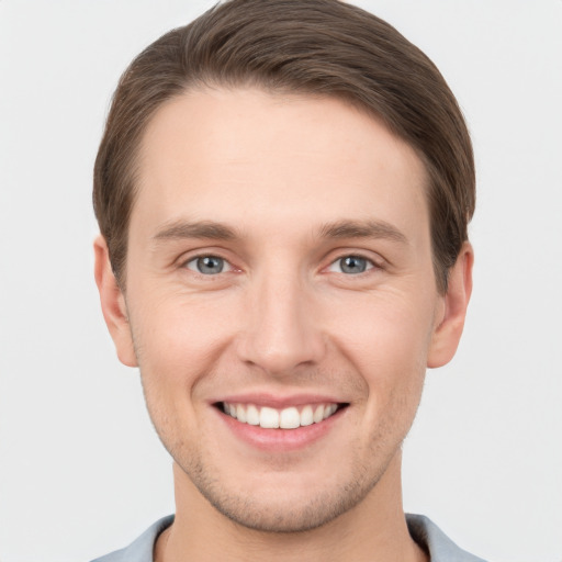 Joyful white young-adult male with short  brown hair and grey eyes