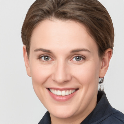 Joyful white young-adult female with short  brown hair and grey eyes