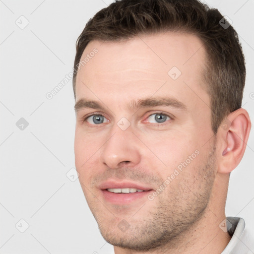 Joyful white young-adult male with short  brown hair and grey eyes