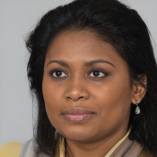 Joyful black young-adult female with long  brown hair and brown eyes