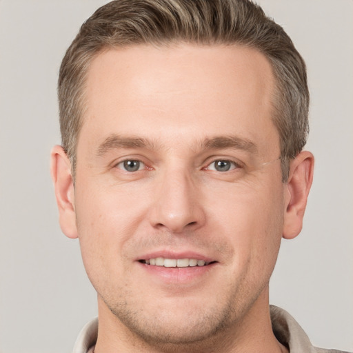 Joyful white young-adult male with short  brown hair and grey eyes