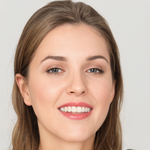 Joyful white young-adult female with long  brown hair and grey eyes