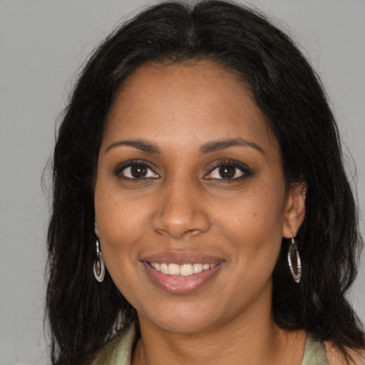 Joyful black young-adult female with long  brown hair and brown eyes