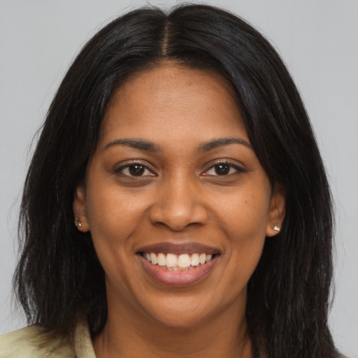 Joyful black young-adult female with long  brown hair and brown eyes