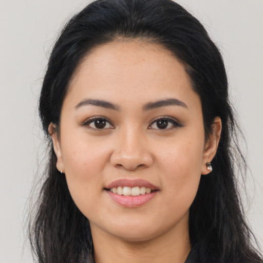 Joyful latino young-adult female with long  brown hair and brown eyes