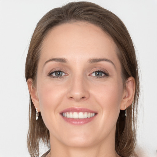 Joyful white young-adult female with medium  brown hair and grey eyes