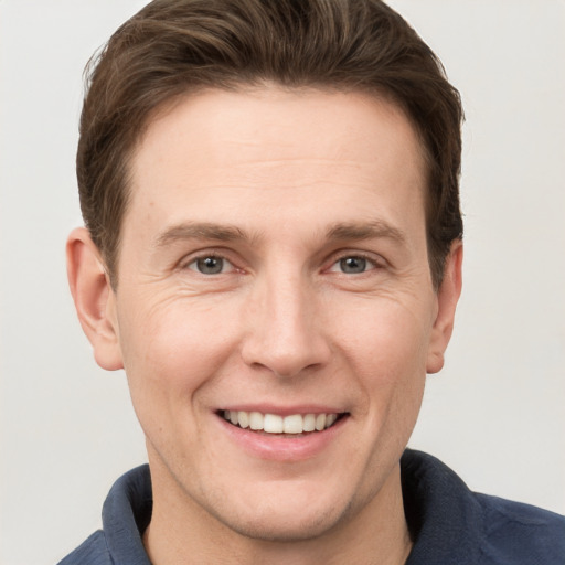 Joyful white adult male with short  brown hair and grey eyes