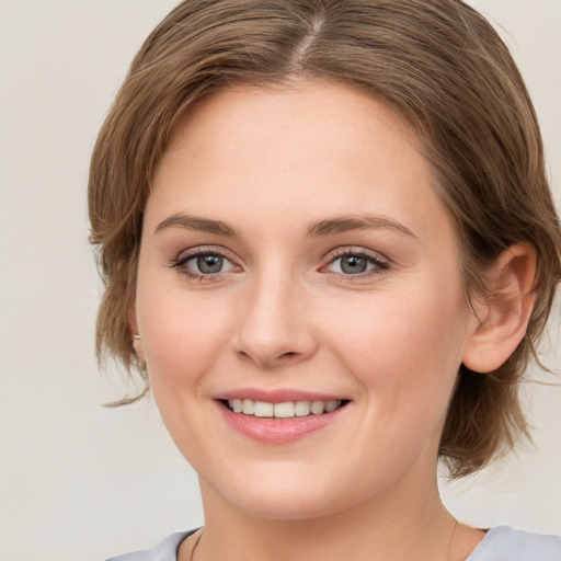 Joyful white young-adult female with medium  brown hair and green eyes