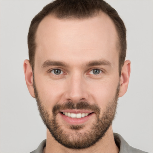 Joyful white young-adult male with short  brown hair and grey eyes