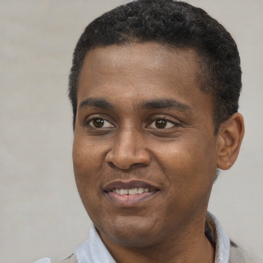Joyful black young-adult male with short  black hair and brown eyes