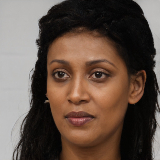 Joyful black young-adult female with long  brown hair and brown eyes