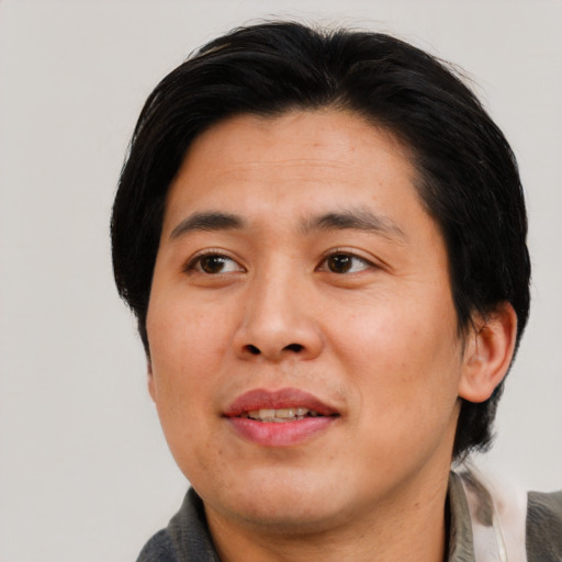 Joyful asian adult male with medium  black hair and brown eyes