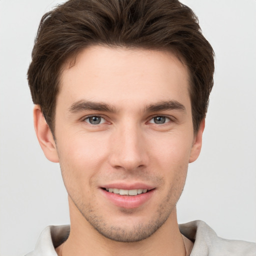 Joyful white young-adult male with short  brown hair and grey eyes