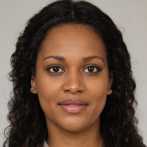 Joyful black young-adult female with long  brown hair and brown eyes