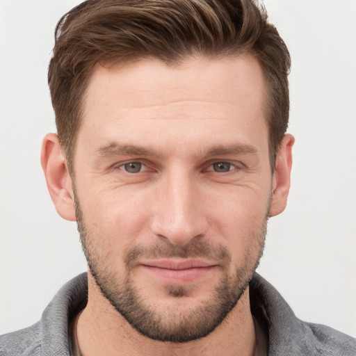 Joyful white young-adult male with short  brown hair and grey eyes