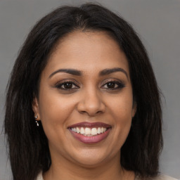 Joyful black young-adult female with long  brown hair and brown eyes