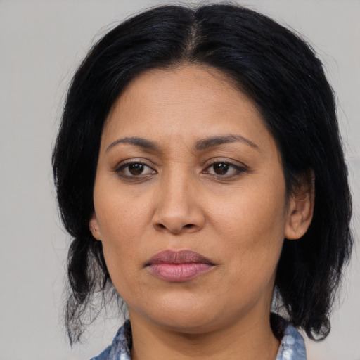 Joyful latino adult female with medium  black hair and brown eyes