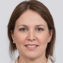 Joyful white young-adult female with medium  brown hair and grey eyes