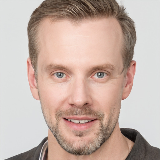 Joyful white adult male with short  brown hair and blue eyes